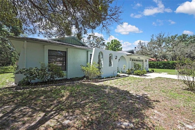 view of front facade with an attached garage, stucco siding, driveway, and a front lawn
