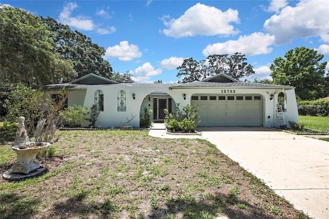 ranch-style home with an attached garage, concrete driveway, stucco siding, and a front lawn