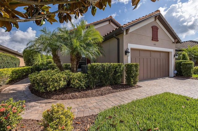 11611 Callisia Dr, Odessa, FL 33556 - mediterranean / spanish house featuring an attached garage, stucco siding, decorative driveway, and a tile roof