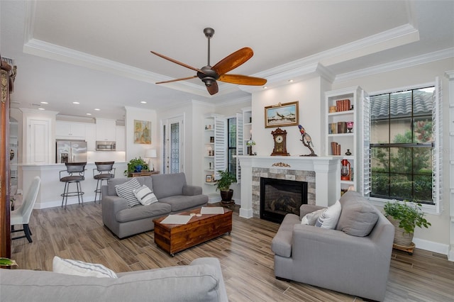 11611 Callisia Dr, Odessa, FL 33556 - living area featuring a ceiling fan, light wood-style flooring, crown molding, a fireplace, and baseboards
