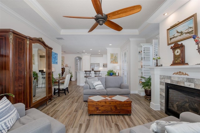11611 Callisia Dr, Odessa, FL 33556 - living room featuring a raised ceiling, light wood finished floors, a ceiling fan, a tiled fireplace, and ornamental molding
