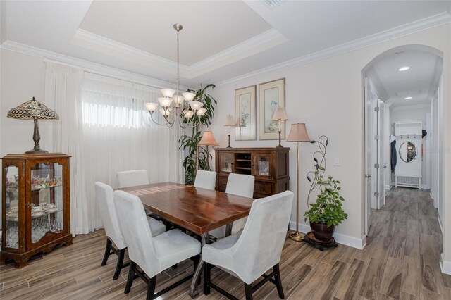 11611 Callisia Dr, Odessa, FL 33556 - dining space featuring arched walkways, light wood finished floors, a chandelier, baseboards, and a tray ceiling