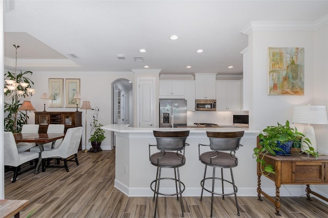 11611 Callisia Dr, Odessa, FL 33556 - kitchen featuring stainless steel appliances, light countertops, a peninsula, wood finished floors, and white cabinetry