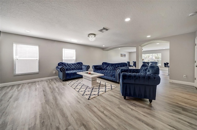6222 Cherry Blossom Trl, Gibsonton, FL 33534 - living room featuring arched walkways, light wood-type flooring, a textured ceiling, baseboards, and recessed lighting