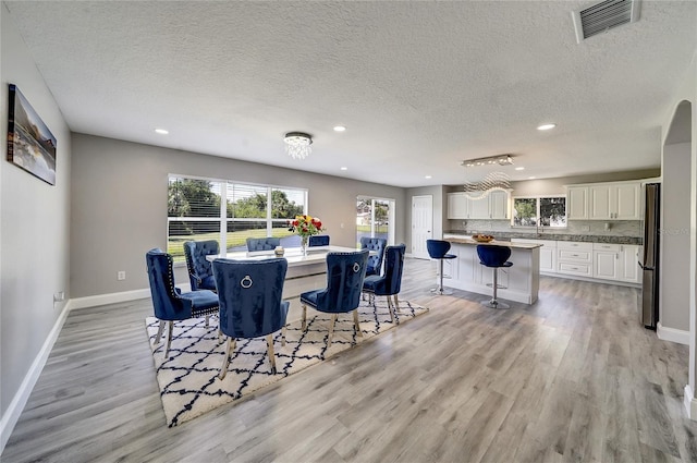 6222 Cherry Blossom Trl, Gibsonton, FL 33534 - dining area with light wood-type flooring, recessed lighting, baseboards, a textured ceiling, and arched walkways