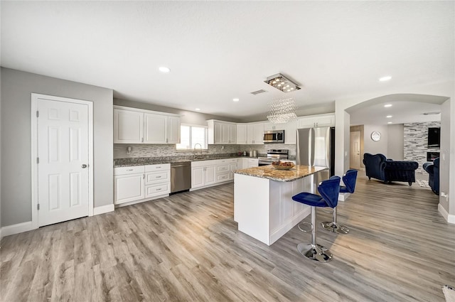6222 Cherry Blossom Trl, Gibsonton, FL 33534 - kitchen featuring stainless steel appliances, arched walkways, light wood-type flooring, a breakfast bar area, and recessed lighting