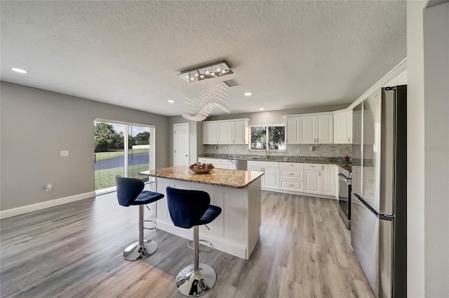 6222 Cherry Blossom Trl, Gibsonton, FL 33534 - kitchen with appliances with stainless steel finishes, a kitchen island, a sink, white cabinetry, and light wood finished floors