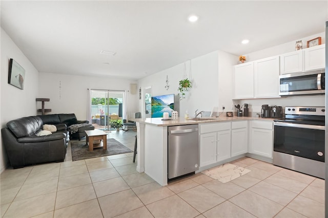 kitchen featuring appliances with stainless steel finishes, open floor plan, a peninsula, white cabinetry, and recessed lighting