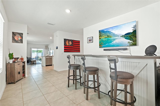 indoor dry bar featuring stainless steel dishwasher, baseboards, light tile patterned flooring, and recessed lighting