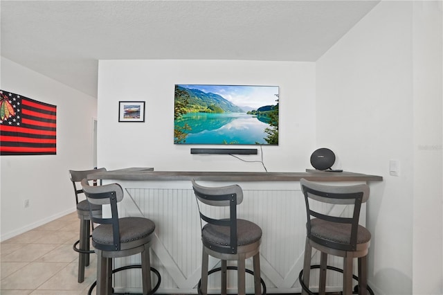 indoor dry bar with baseboards and light tile patterned floors