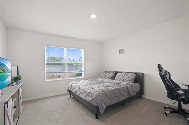 bedroom featuring light carpet, baseboards, and an office area