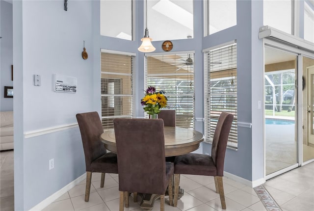dining room featuring light tile patterned flooring, baseboards, and a towering ceiling