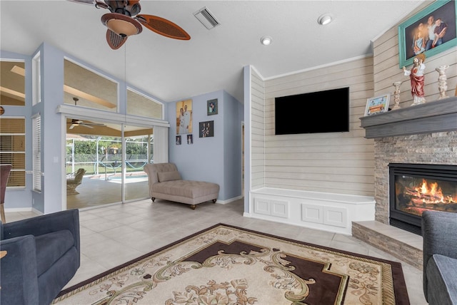 tiled living area with ceiling fan, lofted ceiling, a stone fireplace, baseboards, and recessed lighting