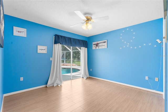 empty room featuring a ceiling fan, baseboards, wood finished floors, and a textured ceiling