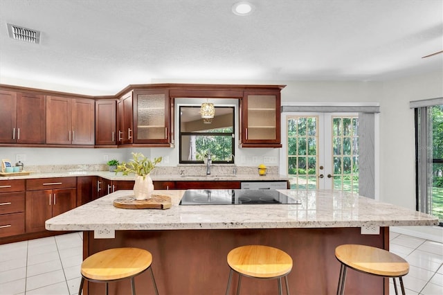 6454 Summerfield Loop, New Port Richey, FL 34655 - kitchen with a sink, black electric cooktop, light tile patterned flooring, glass insert cabinets, and a breakfast bar area