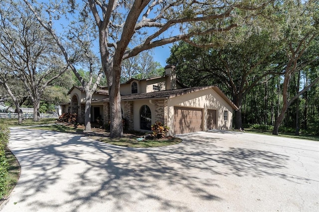 6454 Summerfield Loop, New Port Richey, FL 34655 - mediterranean / spanish-style home with stucco siding, driveway, an attached garage, a chimney, and stone siding
