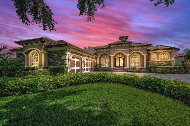 9933 Milano Dr, Trinity, FL 34655 - mediterranean / spanish-style home featuring stone siding, a garage, french doors, a yard, and driveway
