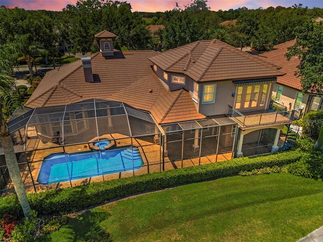 9933 Milano Dr, Trinity, FL 34655 - back of property at dusk with a pool with connected hot tub, a tile roof, a yard, and a patio area