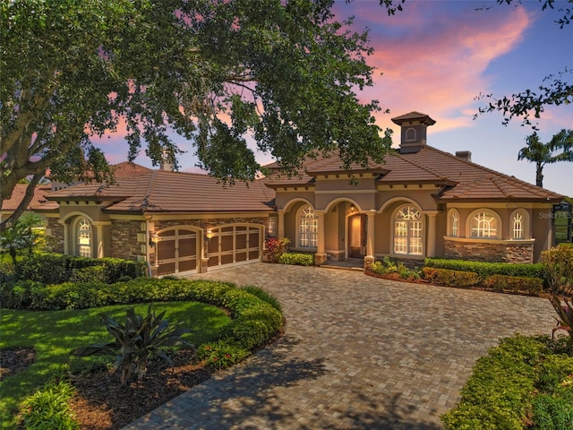 9933 Milano Dr, Trinity, FL 34655 - mediterranean / spanish-style home with stone siding, stucco siding, a garage, and driveway