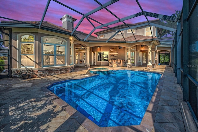 9933 Milano Dr, Trinity, FL 34655 - pool at dusk with french doors, a patio area, a pool with connected hot tub, a ceiling fan, and glass enclosure