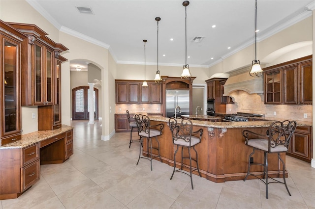 9933 Milano Dr, Trinity, FL 34655 - kitchen with arched walkways, built in fridge, decorative columns, tasteful backsplash, and hanging light fixtures