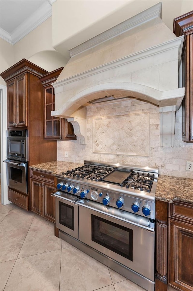 9933 Milano Dr, Trinity, FL 34655 - kitchen featuring range with two ovens, decorative backsplash, dark stone counters, crown molding, and custom exhaust hood