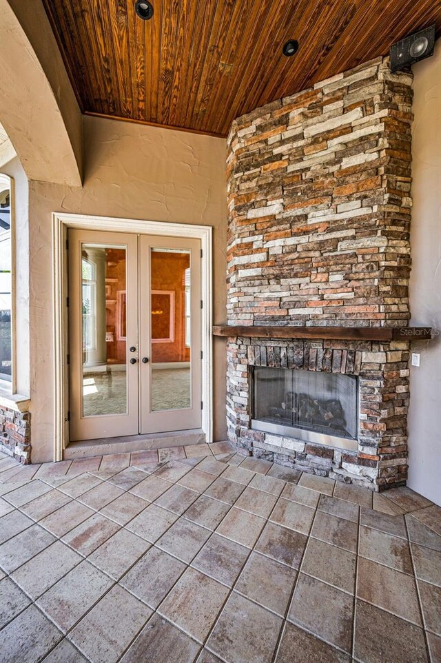 9933 Milano Dr, Trinity, FL 34655 - view of exterior entry with an outdoor stone fireplace, french doors, a patio, and stone siding