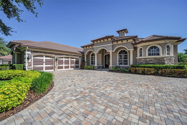 9933 Milano Dr, Trinity, FL 34655 - mediterranean / spanish house featuring an attached garage, stucco siding, driveway, and a tiled roof