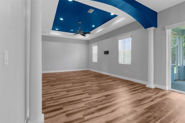 spare room featuring decorative columns, a raised ceiling, a ceiling fan, wood finished floors, and recessed lighting
