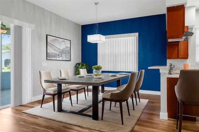 dining room with light wood finished floors, baseboards, and an accent wall