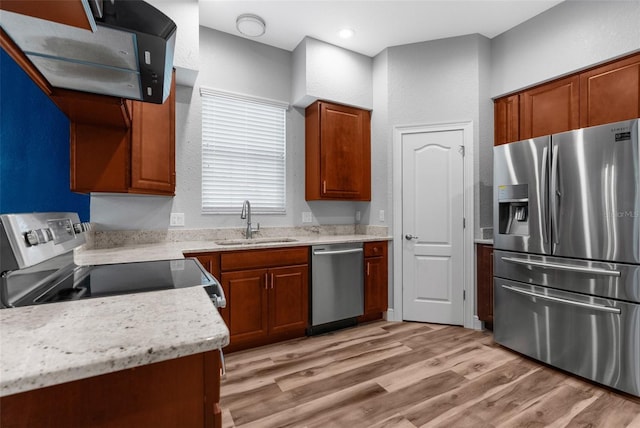 kitchen with appliances with stainless steel finishes, a sink, extractor fan, light wood-style flooring, and brown cabinetry