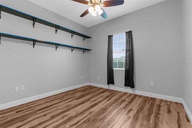 empty room featuring wood finished floors, a ceiling fan, and baseboards