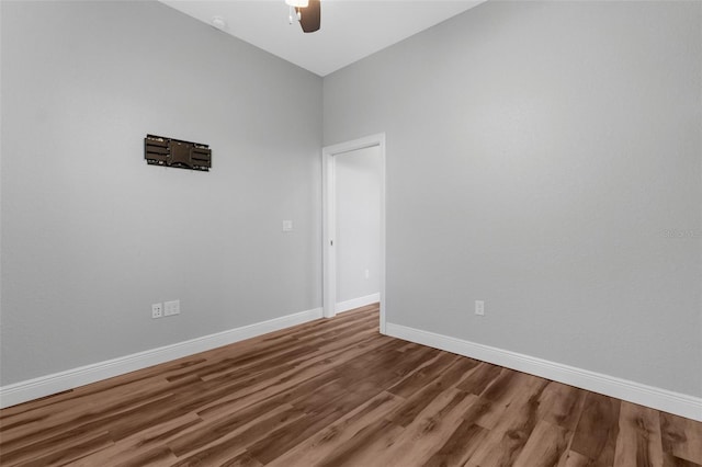 spare room with a ceiling fan, wood finished floors, and baseboards