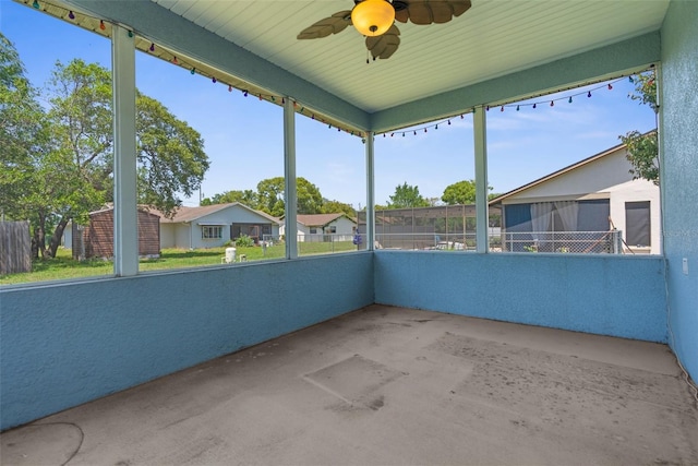 unfurnished sunroom featuring a ceiling fan and a residential view
