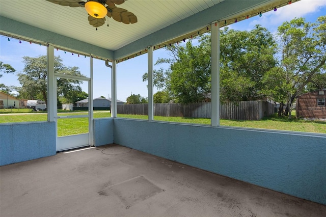 unfurnished sunroom featuring a ceiling fan and plenty of natural light