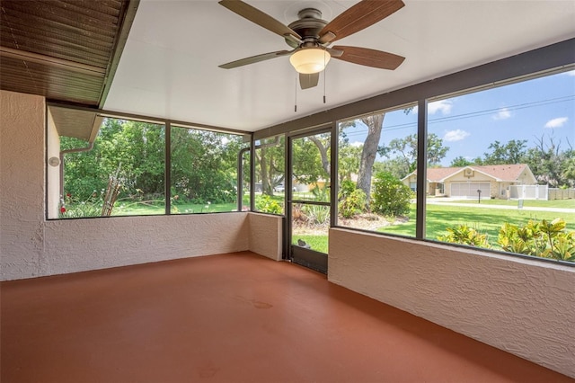 unfurnished sunroom featuring ceiling fan, finished concrete flooring, and a textured wall