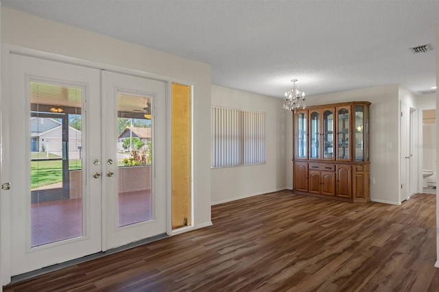 entryway with dark wood-style flooring, a chandelier, baseboards, french doors, and a textured ceiling
