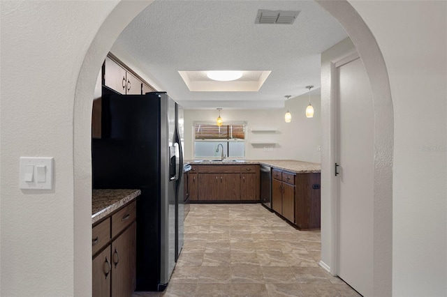 kitchen featuring stainless steel appliances, a sink, decorative light fixtures, and arched walkways