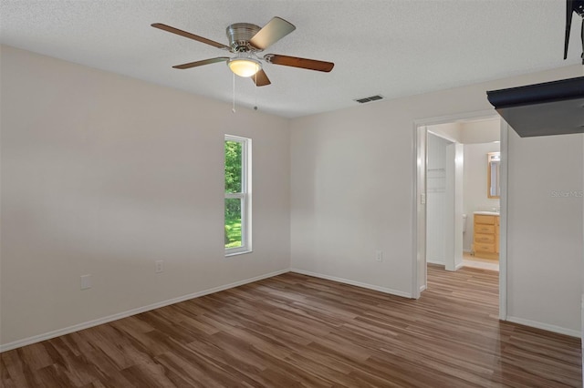 unfurnished room with wood finished floors, ceiling fan, baseboards, and a textured ceiling