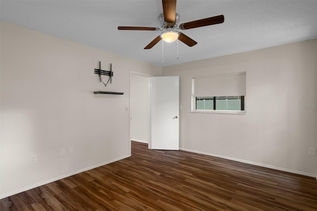 spare room with dark wood-style floors, baseboards, and a ceiling fan