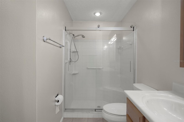 full bath featuring toilet, a textured ceiling, a shower stall, vanity, and tile patterned floors