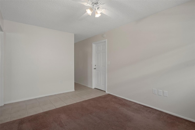 spare room featuring light tile patterned floors, ceiling fan, light carpet, a textured ceiling, and baseboards