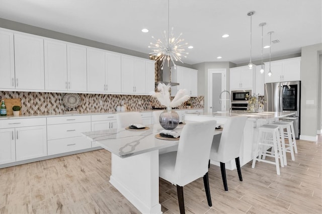 3767 Dragonfly Trl, Odessa, FL 33556 - kitchen featuring appliances with stainless steel finishes, a spacious island, white cabinetry, tasteful backsplash, and light wood-type flooring