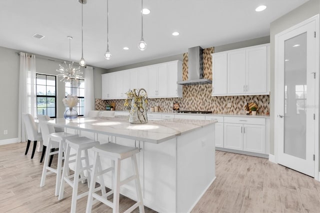 3767 Dragonfly Trl, Odessa, FL 33556 - kitchen featuring wall chimney exhaust hood, a large island, white cabinetry, light stone countertops, and recessed lighting