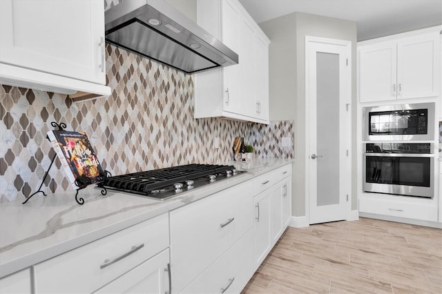 3767 Dragonfly Trl, Odessa, FL 33556 - kitchen featuring wall chimney range hood, stainless steel appliances, white cabinetry, and light stone countertops