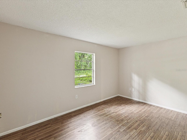 unfurnished room with wood finished floors, baseboards, and a textured ceiling