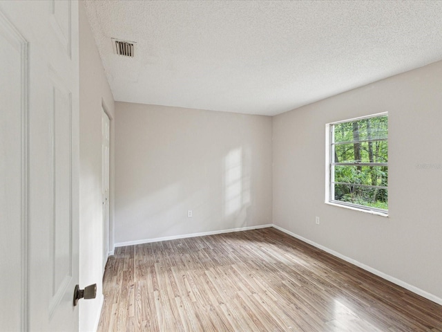unfurnished room with a textured ceiling, wood finished floors, and baseboards