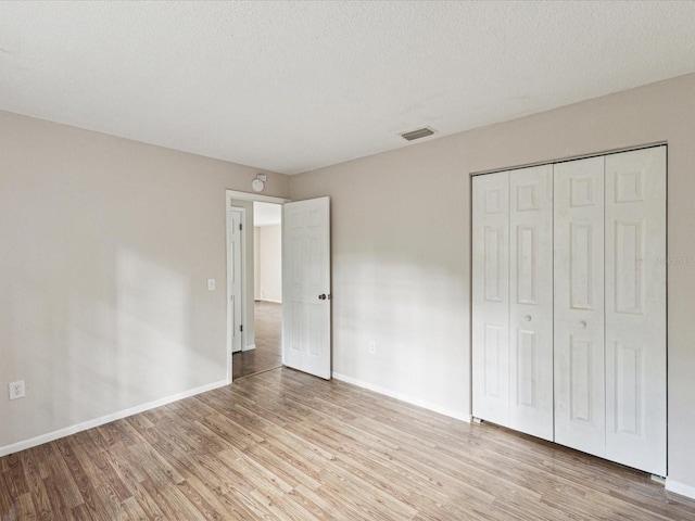 unfurnished bedroom with light wood-style floors, baseboards, and a closet