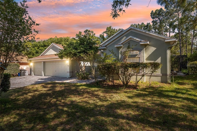 view of front of home featuring a lawn, an attached garage, driveway, and stucco siding