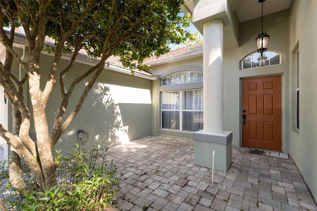 property entrance with stucco siding and a patio
